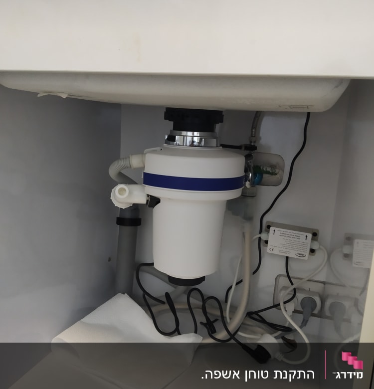 מתקן טוחן אשפה מתחת לכיור עם צינורות וחוטים